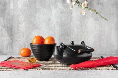 Çaydanlıklı Mandarinler, Japon zarfları ve masada gri grunge arka planına karşı vantilatör. Yeni yıl kutlaması