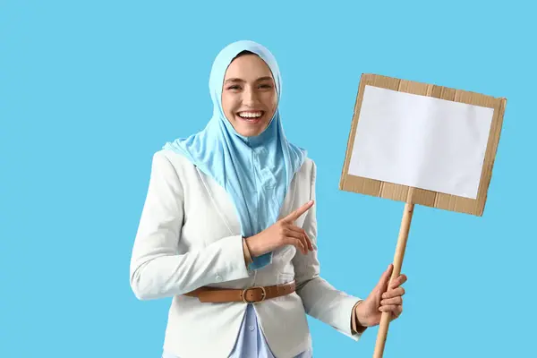 Stylová Muslimská Žena Ukazuje Prázdné Prkno Modrém Pozadí — Stock fotografie