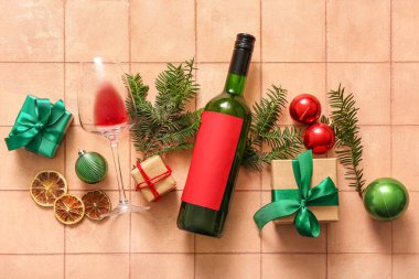 Bir şişe şarap ve pembe fayanslı Noel hediyesi kutuları.
