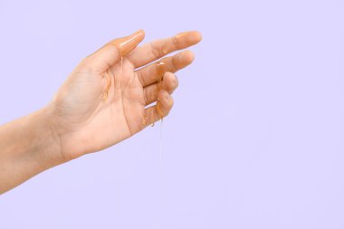 Eline bal damlatan bir kadın, leylak arkaplanı.