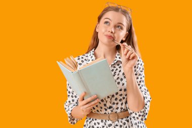 Sarı arka planda gözlüklü ve defterli düşünceli genç bir kadın.