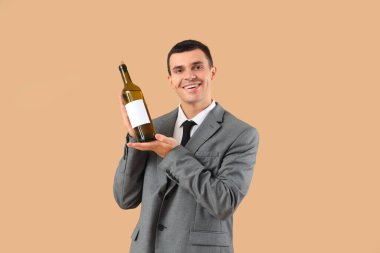 Bej arka planda şarap şişesi olan genç bir şarap garsonu.