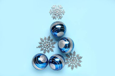 Toplardan yapılmış Noel ağacı ve mavi arka planda dekor kar taneleri