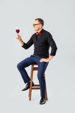 Olgun şarap garsonu, bir bardak kırmızı şarapla arka planda oturuyor.