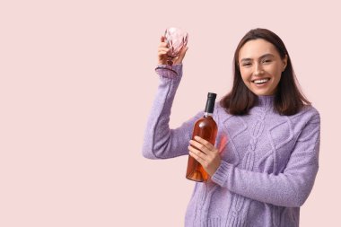 Güzel genç kadın ile cam ve pembe bir arka plan üzerinde kırmızı şarap şişe