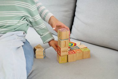 Genç anne ve küçük oğlu evdeki kanepede küplerle oynuyorlar.