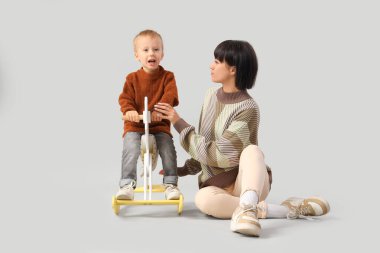 Genç anne ve küçük oğlu hafif arka planda sallanan atın üstünde