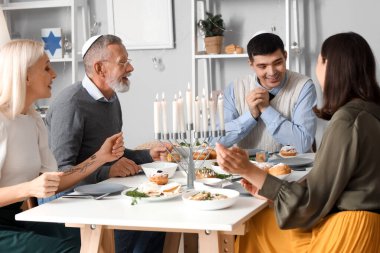 Genç bir adam Hanuka 'da ailesiyle yemek yiyor.