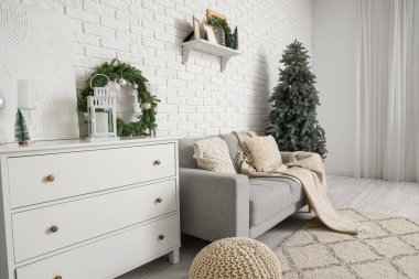 Gri kanepesi, beyaz çekmeceleri ve Noel ağacı olan şenlikli oturma odasının içi.