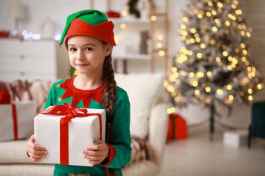 Noel arifesinde evde hediyeli elf kostümlü şirin küçük kız.