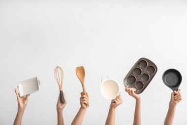 Arka planda farklı mutfak aletleri olan kadın elleri.