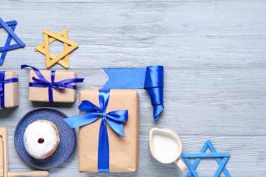 Gri ahşap arka planda Hanuka kutlamaları için hediyeler ve geleneksel semboller içeren kompozisyon
