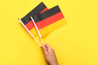 Sarı arka planda Almanya bayrakları olan bir erkek.