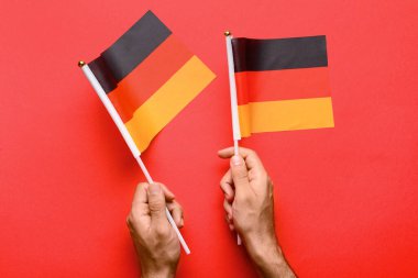 Kızıl zemin üzerinde Almanya bayrakları olan erkek eller
