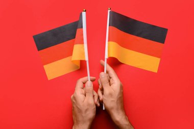 Kızıl zemin üzerinde Almanya bayrakları olan erkek eller