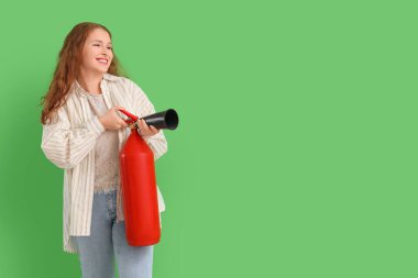 Yeşil arka planda yangın söndürücü olan genç bir kadın.