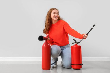 Işığın yanında yangın söndürücüleri olan genç bir kadın.