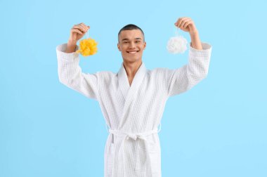 Teenage boy in bathrobe with loofahs on blue background clipart