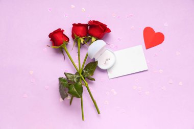 Nişan yüzüğü ve leylak arkaplanda gül çiçekleri olan güzel bir kompozisyon. Sevgililer Günü kutlaması