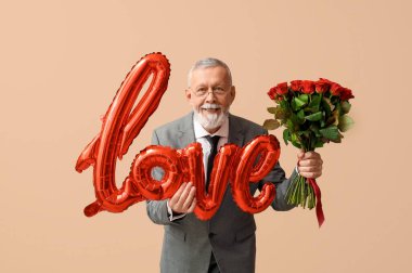 Elinde gül buketi ve hava balonu olan olgun bir adam. Bej arka planda Sevgililer Günü için aşk kelimesi şeklinde.