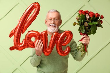 Elinde gül buketi ve hava balonu olan olgun bir adam. Yeşil arka planda Sevgililer Günü için aşk kelimesi şeklinde.