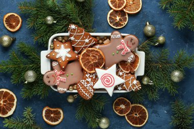 Noel kurabiyeli fırın tabağı ve mavi arka planda kurutulmuş portakal dilimleri.