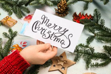 Noel kartı, süslemeler ve arka planda köknar dalları olan bir kadın, yakın plan.