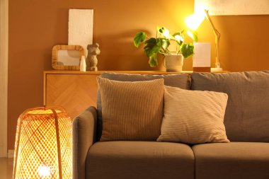 Akşamları gri kanepesi ve parlak lambaları olan modern oturma odasının içinde.