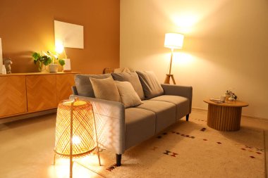 Akşamları gri kanepesi ve parlak lambaları olan modern oturma odasının içinde.