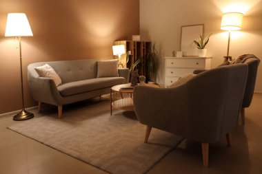 Gri koltuklu, koltuklu, parlak lambalı modern oturma odasının içinde.