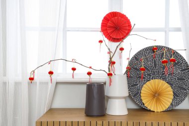 Ağaç dalları olan vazolar, geleneksel Çin fenerleri ve oturma odasındaki ahşap dolapta kağıt vantilatörler. Çin Yeni Yıl Kutlaması