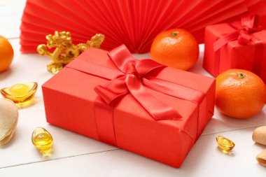 Fal kurabiyeleriyle, mandalinalarla ve beyaz ahşap arka planda Çin sembolleriyle dolu bir hediye kutusu. Yeni yıl kutlaması