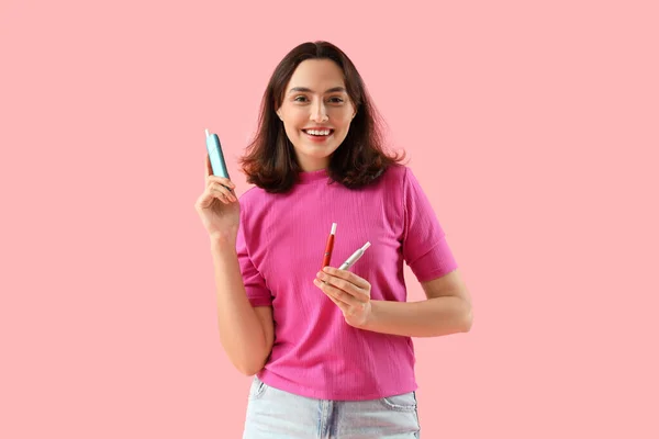 ピンクの背景に電子葉巻を持つ若い女性 — ストック写真