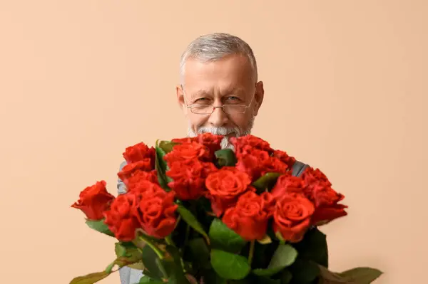 Mature man with bouquet of roses for Valentine's day on beige background