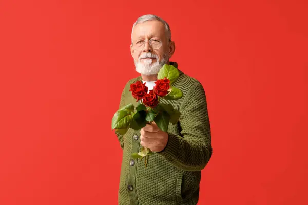 Mature man with rose flowers on red background. Valentine\'s day celebration