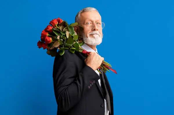 Mature man with bouquet of roses on blue background. Valentine\'s day celebration