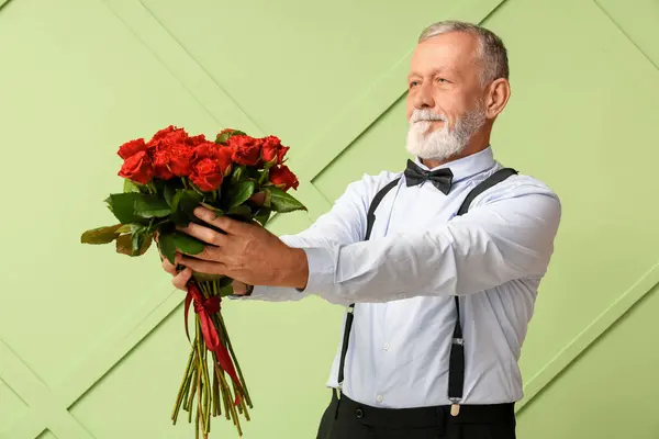 Mature man with bouquet of roses on green background. Valentine\'s day celebration