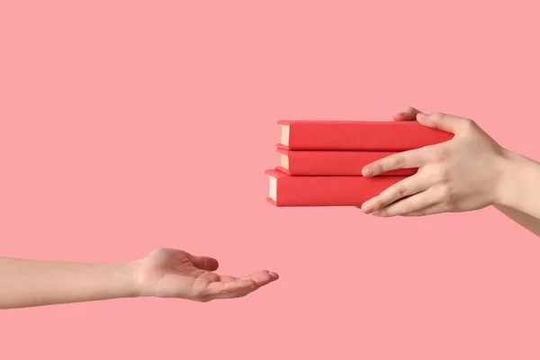 Handen Passeren Stapel Boeken Aan Een Andere Persoon Roze Achtergrond — Stockfoto