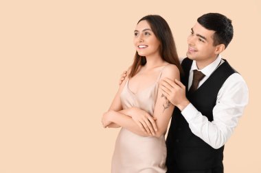 Bej arka planda zarif genç bir çift.