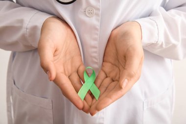 Yeşil Farkındalık Kurdelesi tutan kadın doktor, yakın plan. Ruh Sağlığı Günü