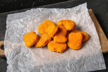 Siyah arka planda lezzetli nuggetları olan kağıt pişirme