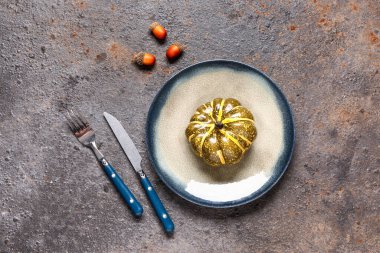 Gri grunge arka planında meşe palamudu ve balkabağı olan şık bir sonbahar sofrası.