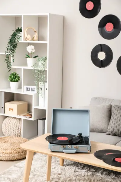Record player with vinyl disks on table in interior of living room