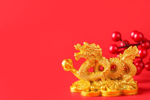 Golden dragon figurine with berries on red background, closeup. Chinese New Year celebration