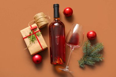 Kahverengi arka planda Noel hediyesi kutusu olan bir şişe ve bir bardak şarap.
