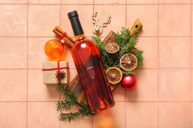 Noel ağacı dallı bir şişe şarap, kurutulmuş portakal ve pembe fayanslı bir hediye kutusu.