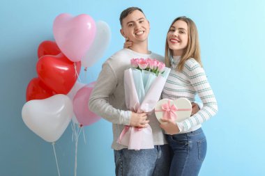 Çiçek buketi, hediye kutusu ve mavi arka planda kalp şeklinde balonları olan sevimli bir çift. Sevgililer Günü kutlaması