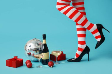 Noel çoraplı, şampanyalı ve mavi arka planda Noel dekoru olan kadın bacakları. Yeni yıl partisi konsepti