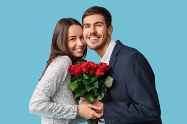 Mavi arka planda kırmızı gül buketi olan güzel genç bir çift. Sevgililer Günü kutlaması