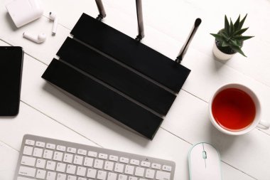 Beyaz ahşap arka planda klavyesi ve kulaklığı olan modern wi-fi yönlendirici